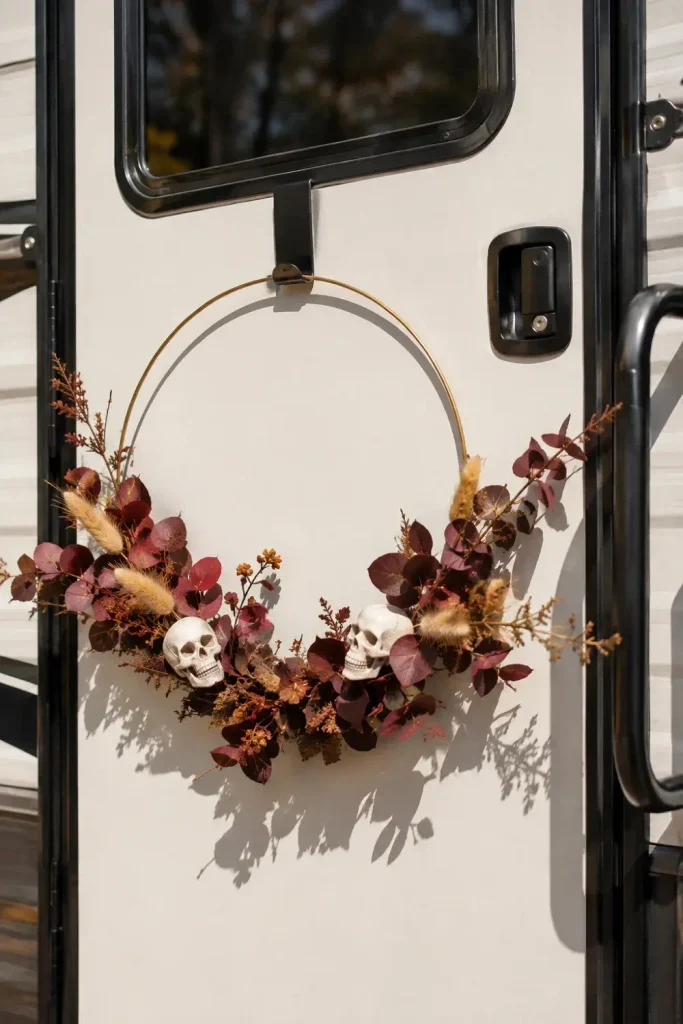 Asymmetrical brass hoop wreath with burgundy eucalyptus and miniature skulls on a camper door.