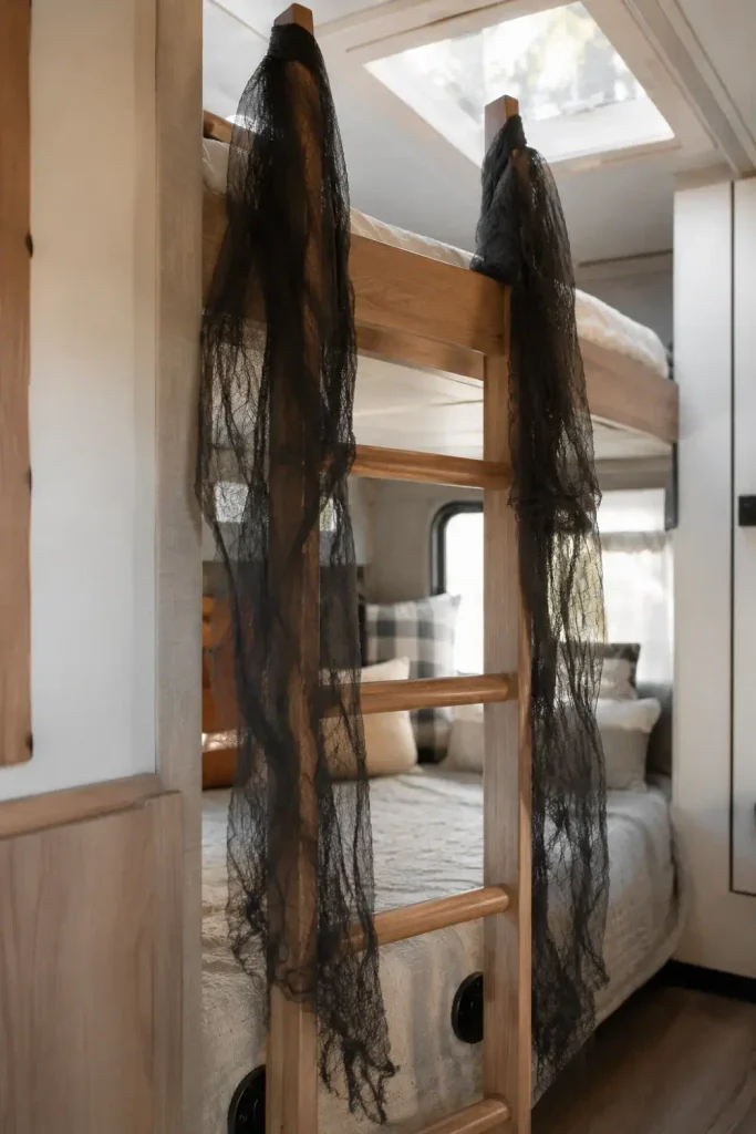 Sheer black spooky cloth draped along the side rails of a wooden camper bunk ladder with steps left clear.