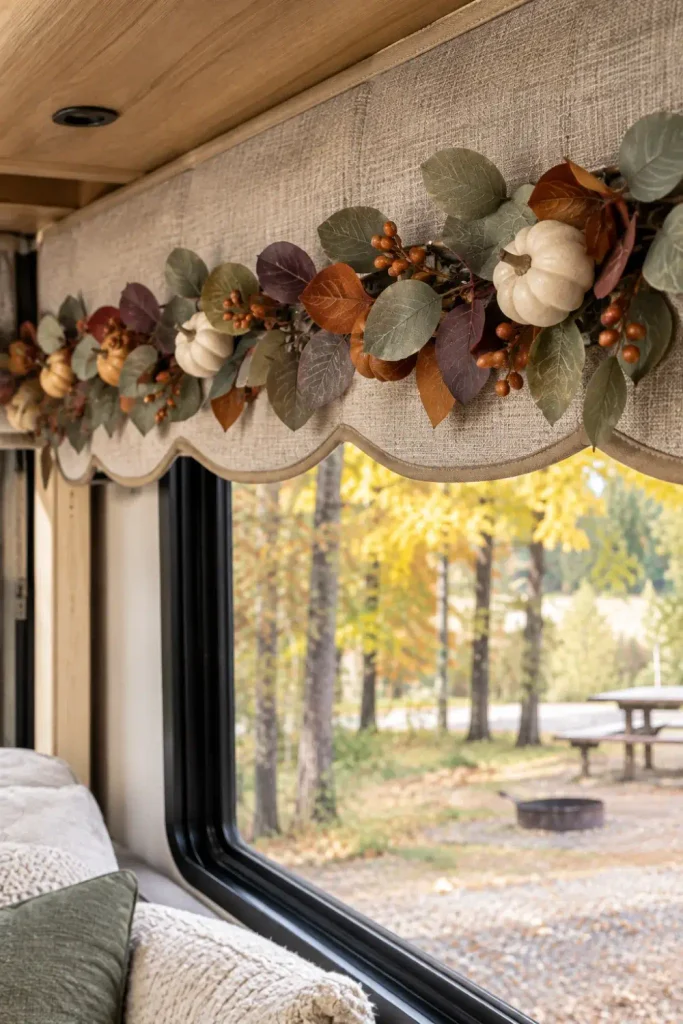 Faux autumn eucalyptus garland with mini foam pumpkins clipped to the scalloped valance of an RV awning.