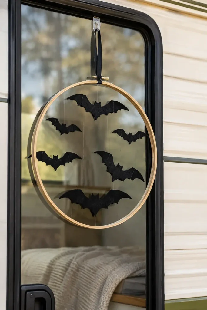 Minimalist bamboo hoop wreath with floating black felt bats hanging on an RV window.