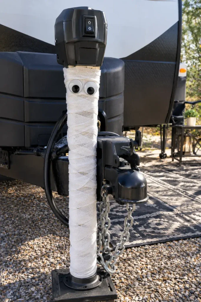 RV electric tongue jack post wrapped in white self-clinging bandages with googly eyes like a mummy.
