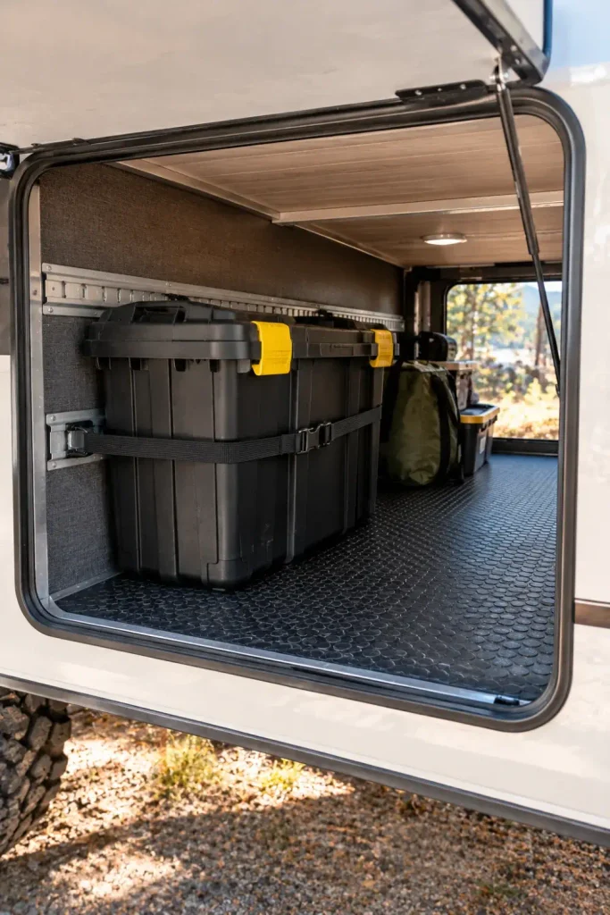 Heavy-duty sealed storage tote strapped inside an RV exterior pass-through cargo compartment.