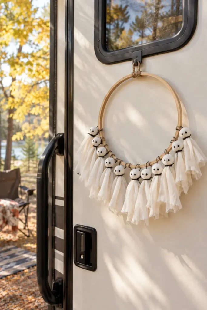 White muslin sheet ghost tassel wreath on a wooden hoop hanging on an RV door.